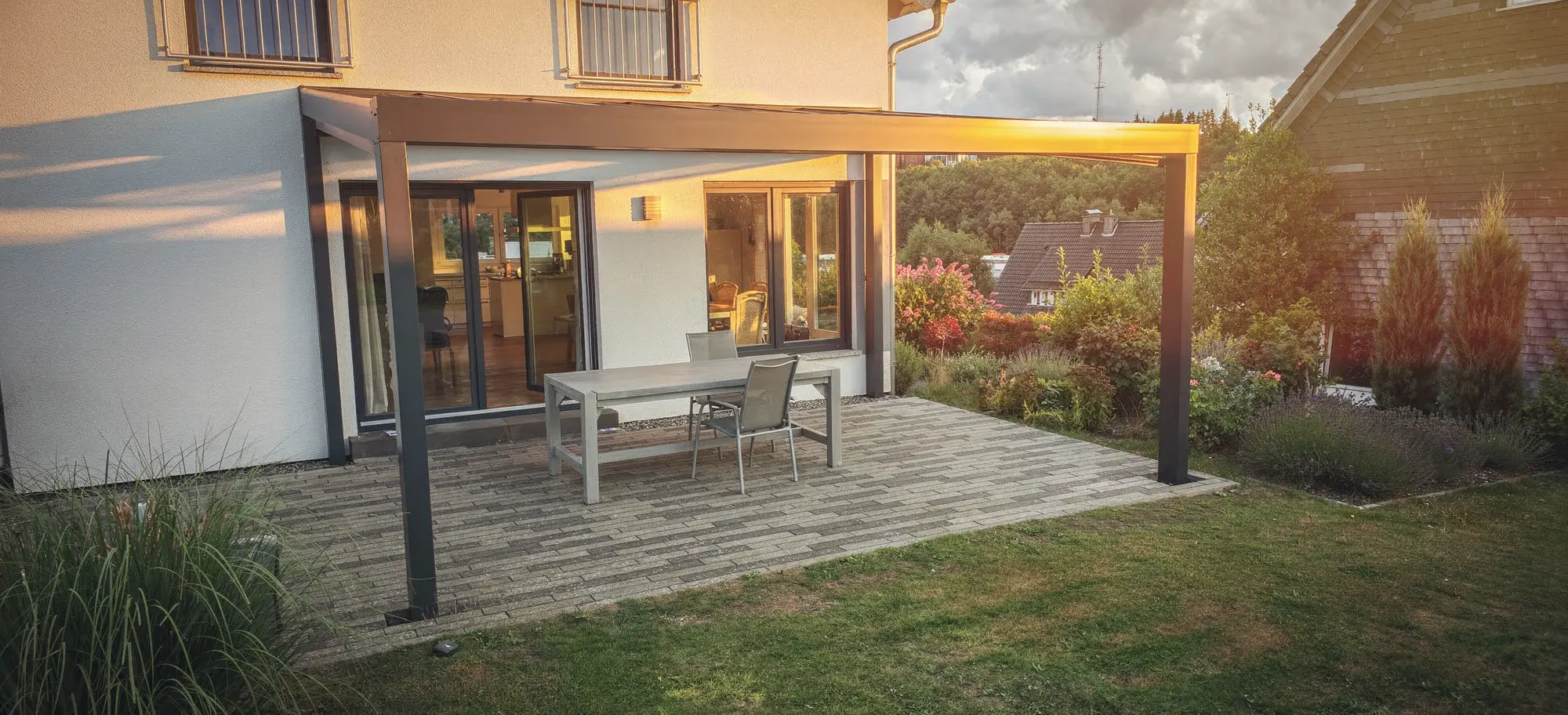 Terrassenüberdachung mit dunklem Gestell und Ausblick auf Garten