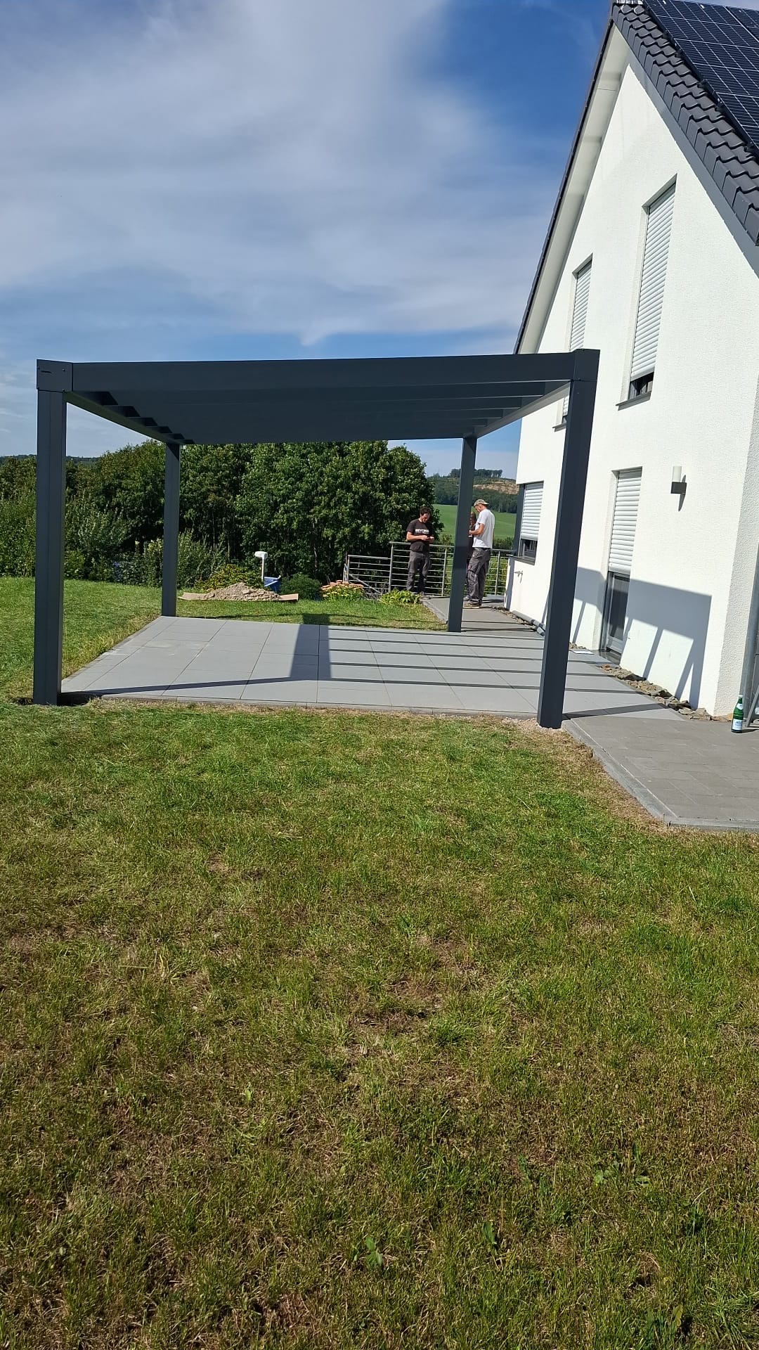 Terrassenüberdachung mit schwarzem Gestell und Terrassenbereich