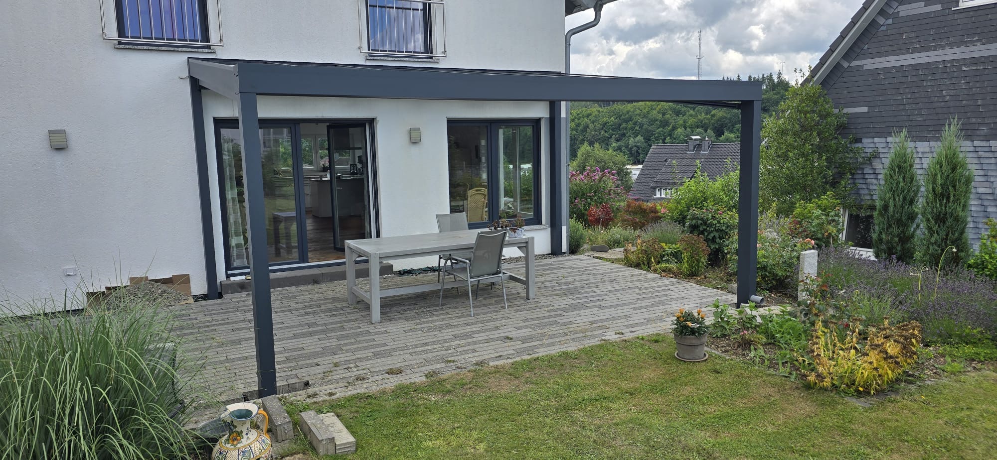 Terrassenüberdachung mit schwarzem Rahmen und Ausblick